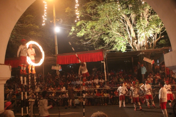 Flame throwers watching a man balancing on one stilt